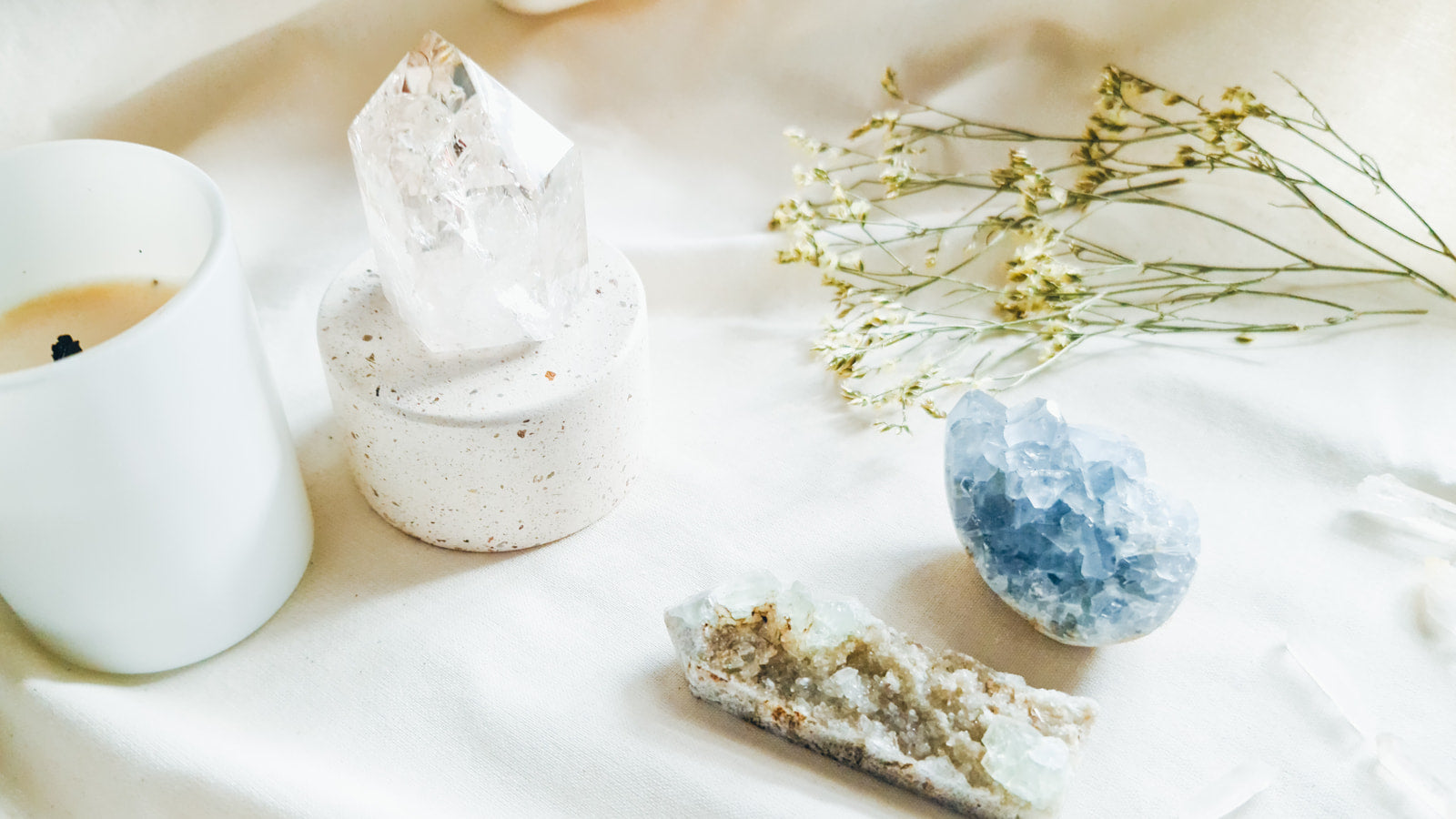 A candle, a clear quartz point, and other quartz crystals