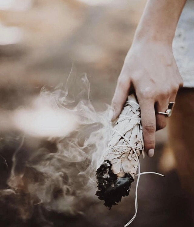 A woman holding a material similar to incense, with smoke rising from her hand